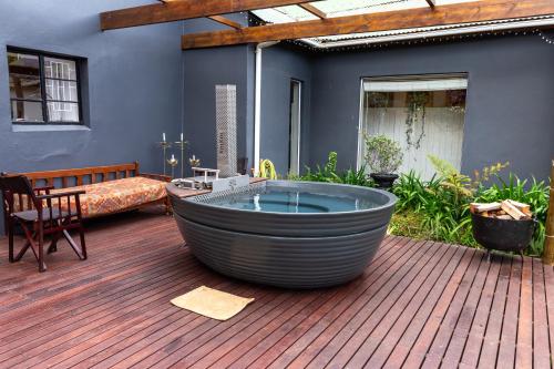 a large tub sitting on a wooden deck with a couch at Sionsberg Farmstay in Riversdale