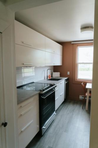 a kitchen with white cabinets and a black stove at Beecomb House Modern Water View House in Charlottetown