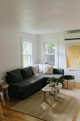 a living room with a black couch and a table at Beecomb House Modern Water View House in Charlottetown