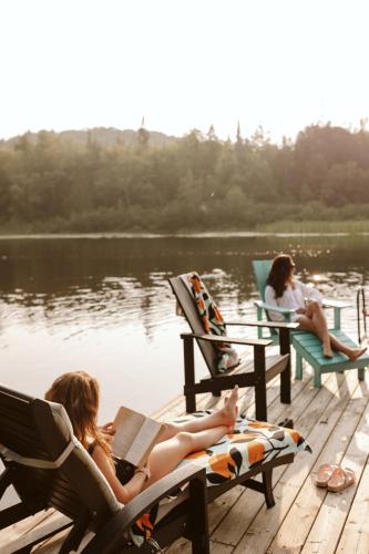 two women sitting in lawn chairs on a dock near a lake at Wolegib Waterfront Retreat in Muskoka in Huntsville