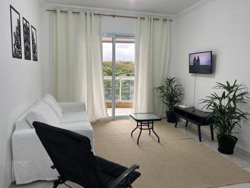 a white living room with a white couch and a desk at Apartamento Poleto's in Bertioga