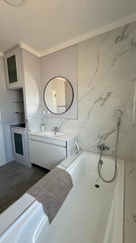 a white bathroom with a tub and a sink at vila pinheiro in Bias do Norte
