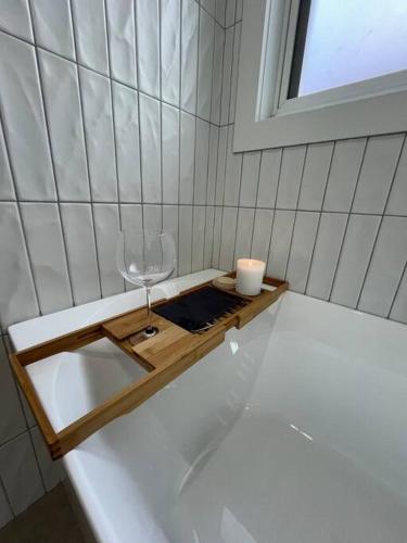 a bath tub with a wine glass and a candle at Baxter Cottage in Bendigo