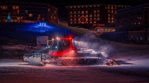a bulldozer is blowing snow on a street at night at New Gudauri Neo Apartments in Gudauri