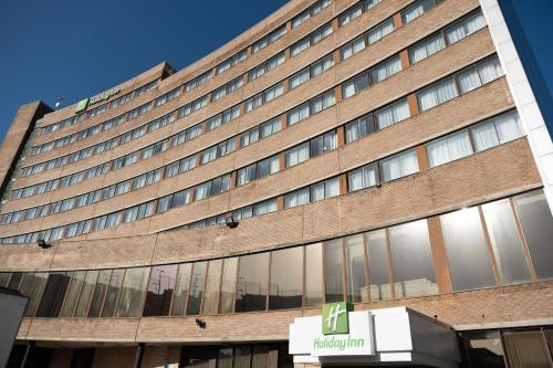 a large brick building with a sign in front of it at Holiday Inn Preston by IHG in Preston