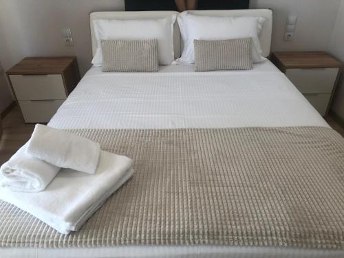 a large bed with white sheets and pillows on it at Brand new renovated apartment by the stadium in Aridaia