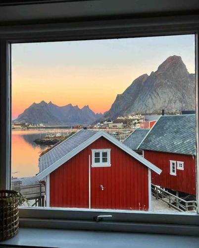 a view of a red house from a window at Reine Front View - Mountain & Seaview in Reine