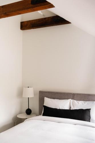 a bedroom with a bed with white sheets and wooden beams at Maison Rasco by Luxury In Transit in Montréal