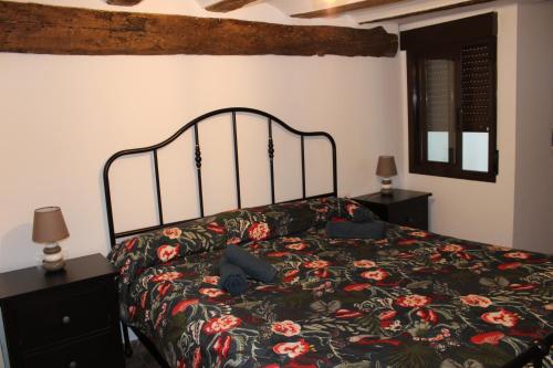a bedroom with a bed with a floral bedspread at Apartamentos Patas y Patetas in Tragacete
