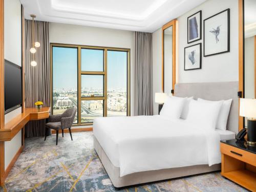 a hotel room with a bed and a desk and a television at voco Jeddah Gate by IHG in Jeddah