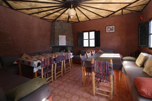 a living room with tables and chairs and a room with a unintention at Gite Ogog Tacheddirt in Tacheddirt