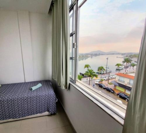 a room with a window with a bed and a view at Excepcional apartamento central e perto da praia in Cabo Frio