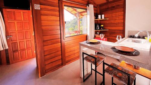 a kitchen with a counter and a sink and a window at Sítio Balango: Seu refúgio em Domingos Martins. Chalés para casais e casa para grupo de pessoas in Domingos Martins