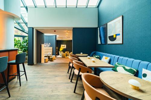 a restaurant with blue walls and wooden tables and chairs at voco Vienna Prater by IHG in Vienna