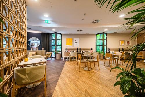 a restaurant with tables and chairs and windows at voco Vienna Prater by IHG in Vienna