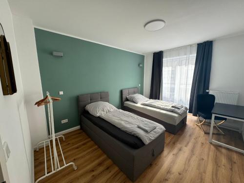 City-Krefeld Luxus 3 Zimmer Apartment mit Balkon في كريفيلد: سريرين في غرفة مع طاولة ومكتب