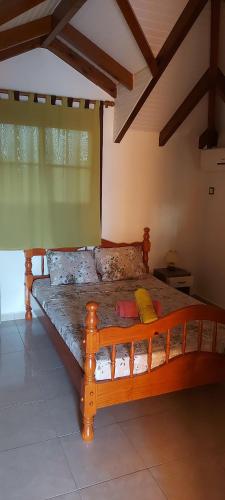 ein Holzbett in einem Zimmer mit Fenster in der Unterkunft HAUT DE VILLA VU SUR LA MONTAGNE. in Saint-Louis