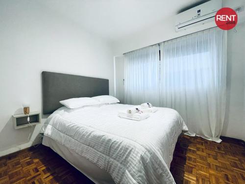a bedroom with a bed with a white blanket and a window at Rent Aguero in Buenos Aires