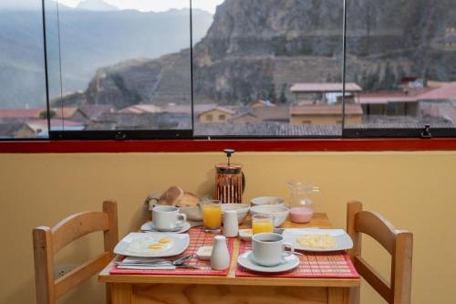 a table with breakfast food and a view of a mountain at Kamma Guest House in Ollantaytambo