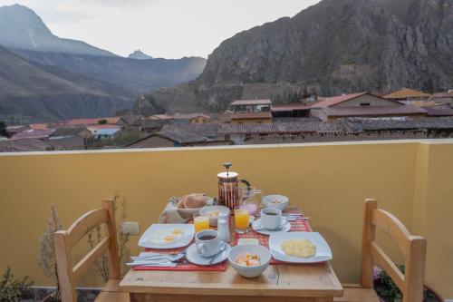 a table with food on it with a view of mountains at Kamma Guest House in Ollantaytambo