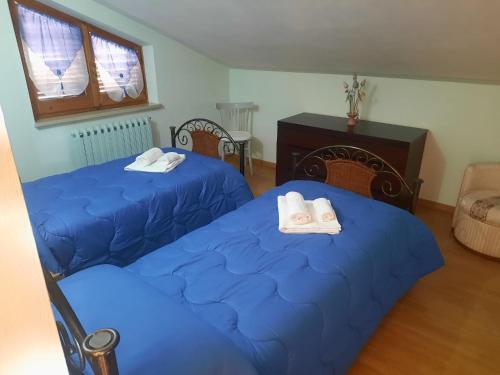 two beds in a room with blue sheets at Appartamento Rosanna in Spoleto