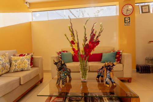 a living room with a couch and a vase with flowers at Kamma Guest House in Ollantaytambo