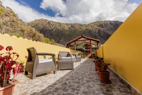 a row of chairs on a patio with mountains in the background at Kamma Guest House in Ollantaytambo