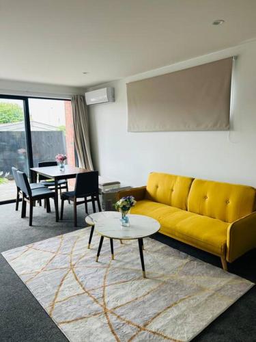 a living room with a yellow couch and a table at The perfect Christchurch Escape in Christchurch