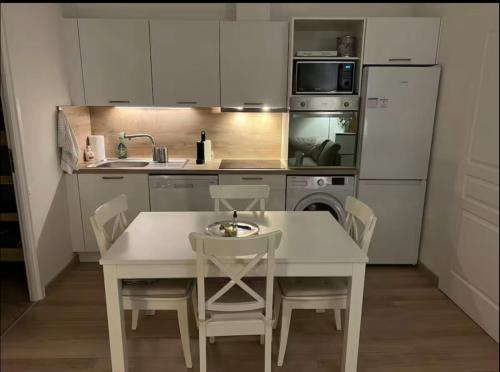La cuisine est équipée d'une table et de chaises blanches ainsi que d'un réfrigérateur. dans l'établissement Appartement 3p - Vieux village VilleFranche/Mer., à Villefranche-sur-Mer