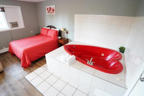 a bathroom with a red bath tub with a bed at Falcon Inn in Niagara Falls