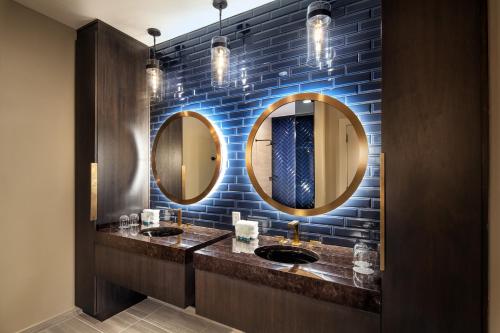 a bathroom with two sinks and two mirrors at The Westin Oaks Houston at the Galleria in Houston