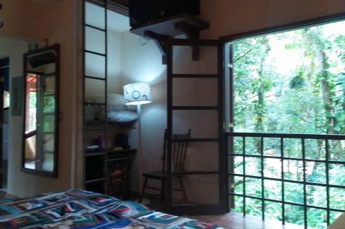 a bedroom with a large window with a view of a tree at Casa de campo na praia in São Sebastião