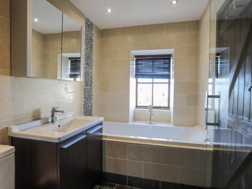 ein Badezimmer mit Badewanne und Waschbecken und einem Fenster in der Unterkunft Tai Ffolt in Pwllheli