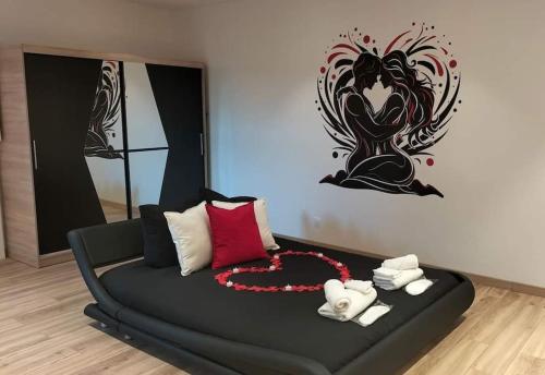 a bedroom with a black bed with a painting on the wall at La Suite Romantique in Rethel