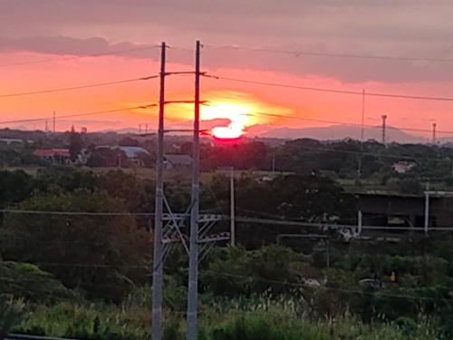 a sunset over a field with two telephone poles at Sunset Suite in Iloilo City