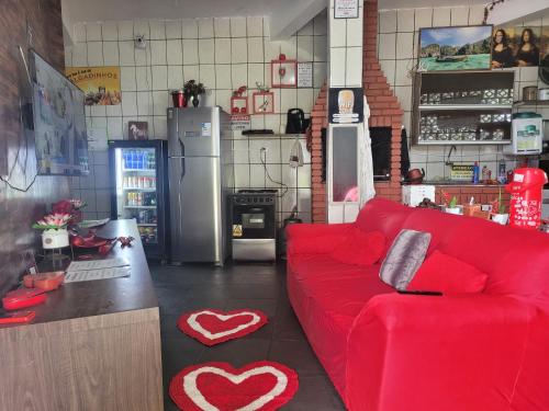 a living room with a red couch and a kitchen at Unidades 1 e 2 e 3 Pousada do Sossego Mar e Verde in Itanhaém