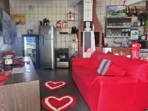 a living room with a red couch in a kitchen at Unidades 1 e 2 e 3 Pousada do Sossego Mar e Verde in Itanhaém