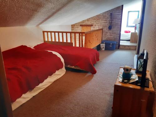 - une chambre avec 2 lits et une couette rouge dans l'établissement Studio Duplex 8 personnes Vue à couper le souffle, à Saint-Honoré