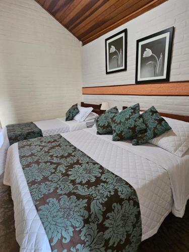 two beds in a hotel room with two bedsvisor at Pousada Recanto João de Barro in Cunha
