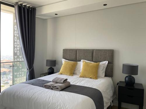 Un dormitorio con una gran cama blanca con almohadas amarillas. en Your Oasis in Waterfall City, en Midrand