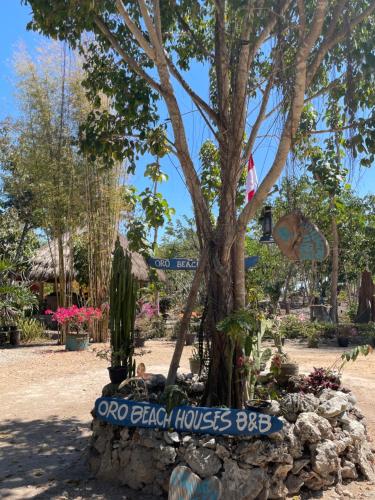 a sign in front of a tree in a park at Oro Beach Houses in Weetebula