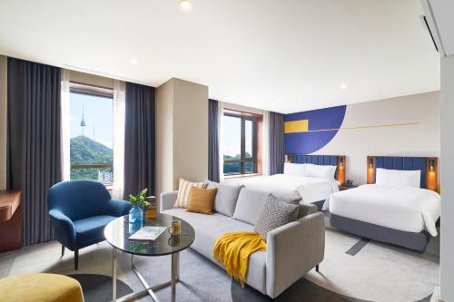 a hotel room with a couch and two beds at voco Seoul Myeongdong by IHG in Seoul