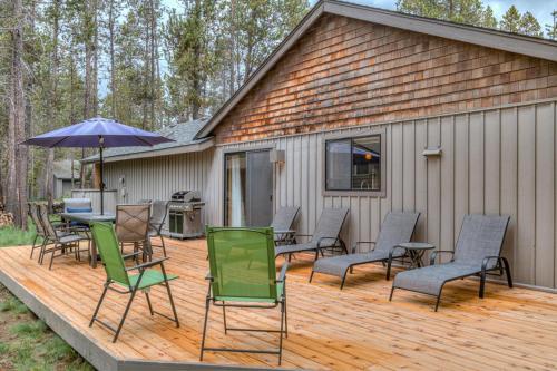 a deck with chairs and a table and an umbrella at Kinglet - Unit 46 in Sunriver