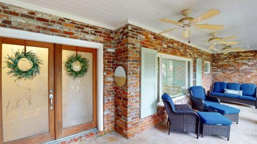 un portico in mattoni con sedie e ventilatore a soffitto di MEET ME AT SUNSET home a Jekyll Island