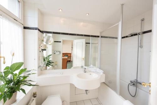 ein weißes Bad mit einem Waschbecken und einer Dusche in der Unterkunft Hotel Kaiserhof Eisenach in Eisenach