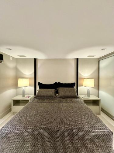a bedroom with a large bed with two lamps at Premier Apartment - Hotel Mercure Belém Boulevard in Belém