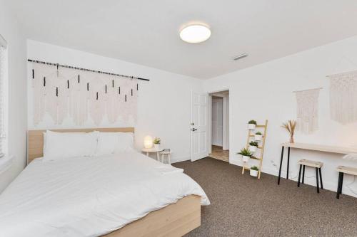 a white bedroom with a large bed and a desk at Relaxing 3-Bedroom With 150 Inch Projector & Pool Table in Jacksonville