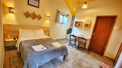 a bedroom with a bed and a table and a door at Chalé Sunset in Miguel Pereira