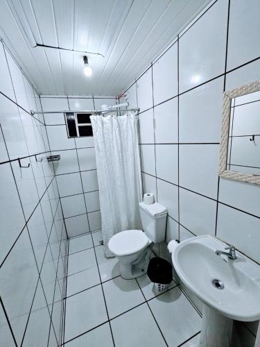 a white bathroom with a toilet and a sink at Cantinho da Nonna in Morretes