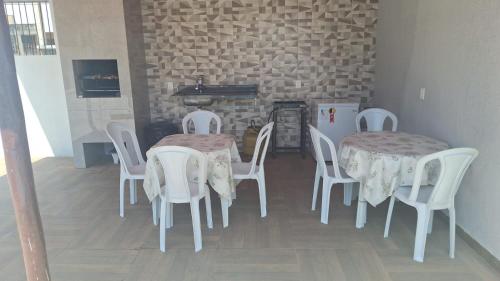 a dining room with two tables and white chairs at Nossa Casa com Piscina in Guarapari